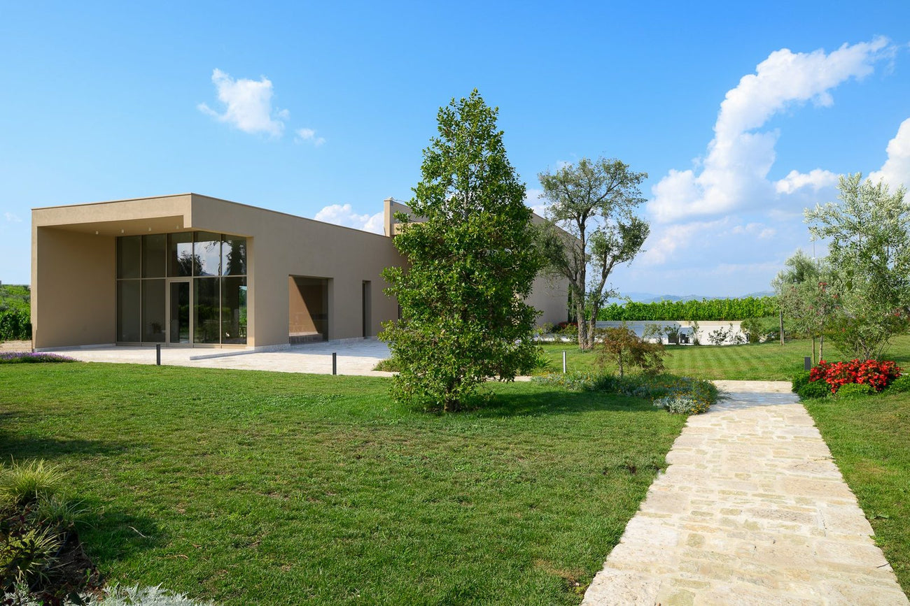 La nuova cantina color sabbia con il giardino e il vialetto in pietra